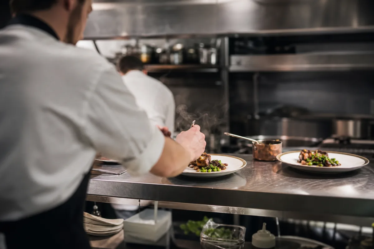 Cuisine de restaurant en pleine activité avec un chef qui dresse une assiette